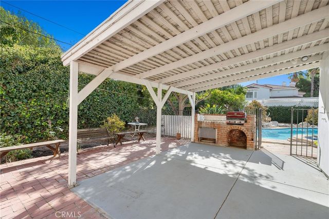 a view of a patio with table and chairs under an umbrella with a large tree