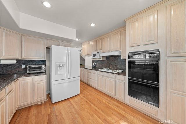 a kitchen with granite countertop white cabinets and stainless steel appliances
