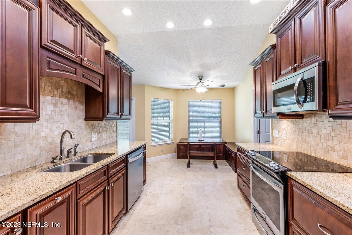 4616 Estates Street Macclenny, FL 32063 - Photo 11 of 32 a kitchen with stainless steel appliances granite countertop a sink stove and microwave