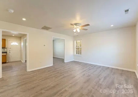 an empty room with wooden floor and a ceiling fan