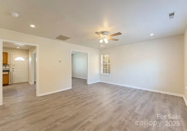 an empty room with wooden floor and a ceiling fan
