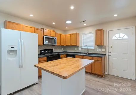 a kitchen with stainless steel appliances granite countertop a refrigerator a sink and a stove