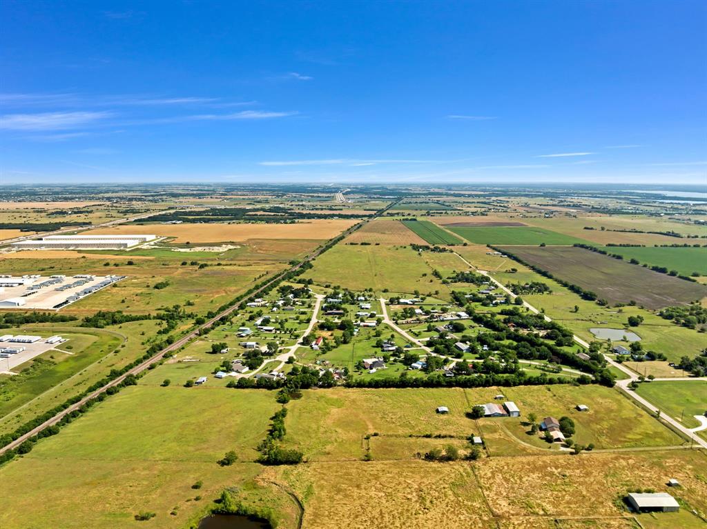 1795 Melton Road Sanger, TX 76266 - Photo 13 of 17 Expansive aerial view showcasing agricultural fields, a residential settlement, and distant commercial buildings under a clear sky