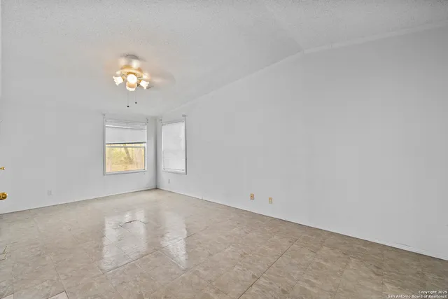 an empty room with a window and a chandelier fan