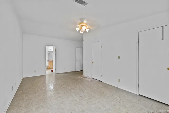 a view of an empty room with a chandelier fan