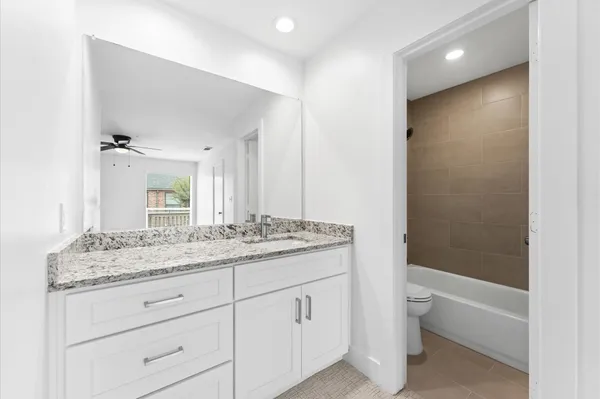 a bathroom with a granite countertop sink a toilet and bathtub