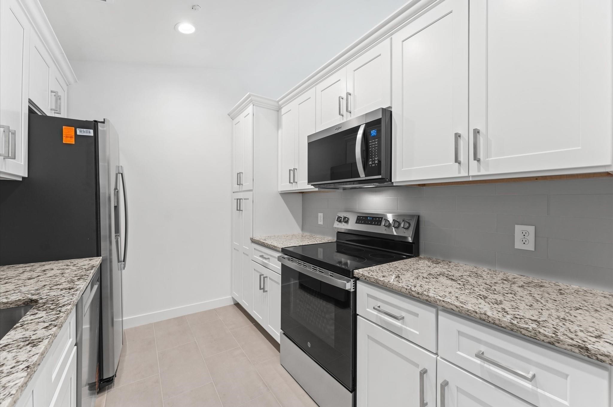2829 Timmons Lane, Unit 202 Houston, TX 77027 - Photo 5 of 17 a kitchen with stainless steel appliances granite countertop a stove a microwave and a refrigerator
