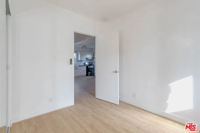 a view of a hallway with wooden floor and a bathroom