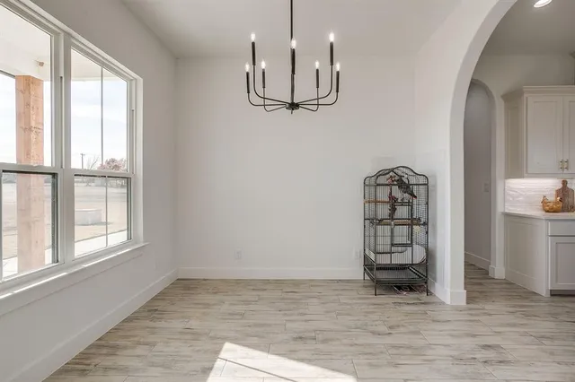 a view of a hallway with wooden floor windows and a kitchen view