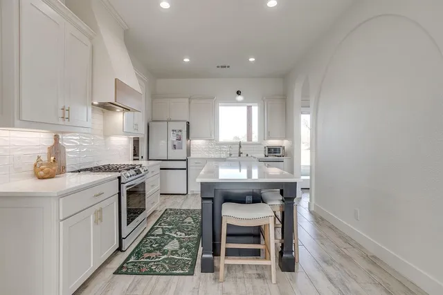 a kitchen with granite countertop a table chairs sink and cabinets
