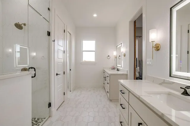 a bathroom with double vanity sink a mirror and a shower