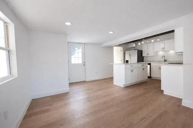 a view of a kitchen with a sink wooden cabinets and a window