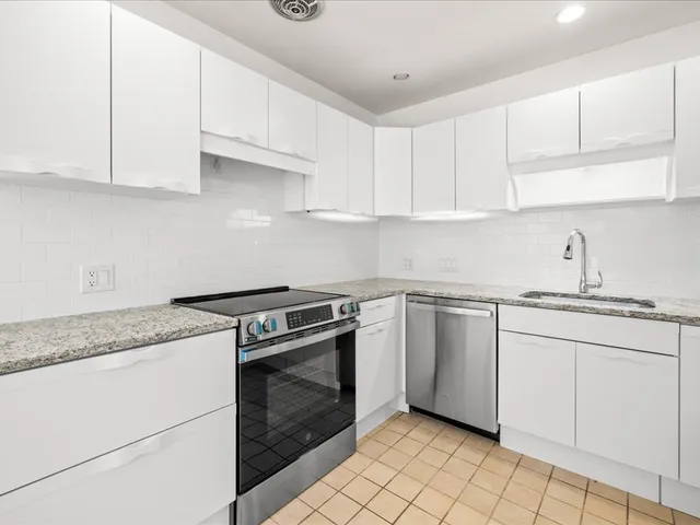 a kitchen with granite countertop white cabinets and white appliances
