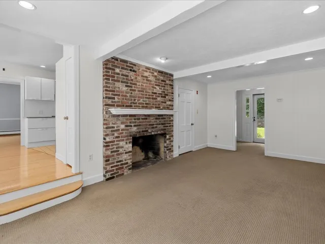 an empty room with a fireplace cabinet and windows