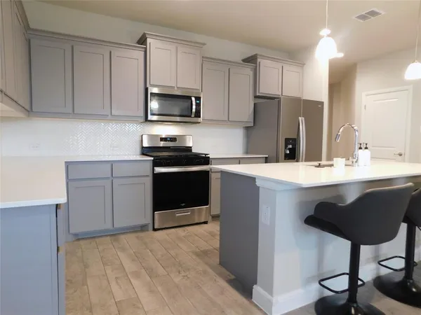 a kitchen with kitchen island granite countertop a sink a counter top space appliances and cabinets