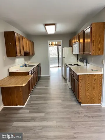 a kitchen with a stove a sink a refrigerator and wooden floor