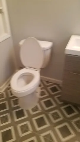 a view of a hallway with wooden floor and a bathroom