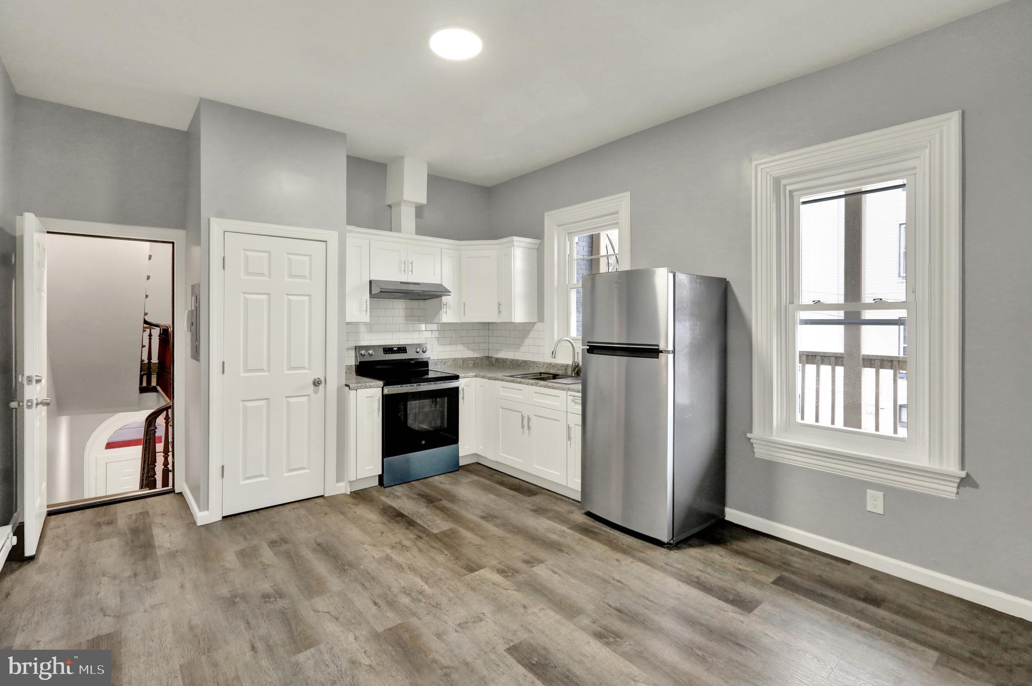 a kitchen with granite countertop white cabinets and refrigerator