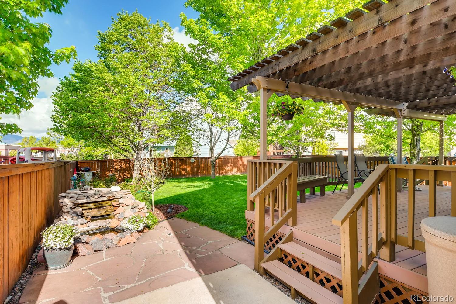9840 South Castle Ridge Circle Highlands Ranch, CO 80129 - Photo 26 of 28 a view of a deck with a table and chairs under an umbrella with a small yard