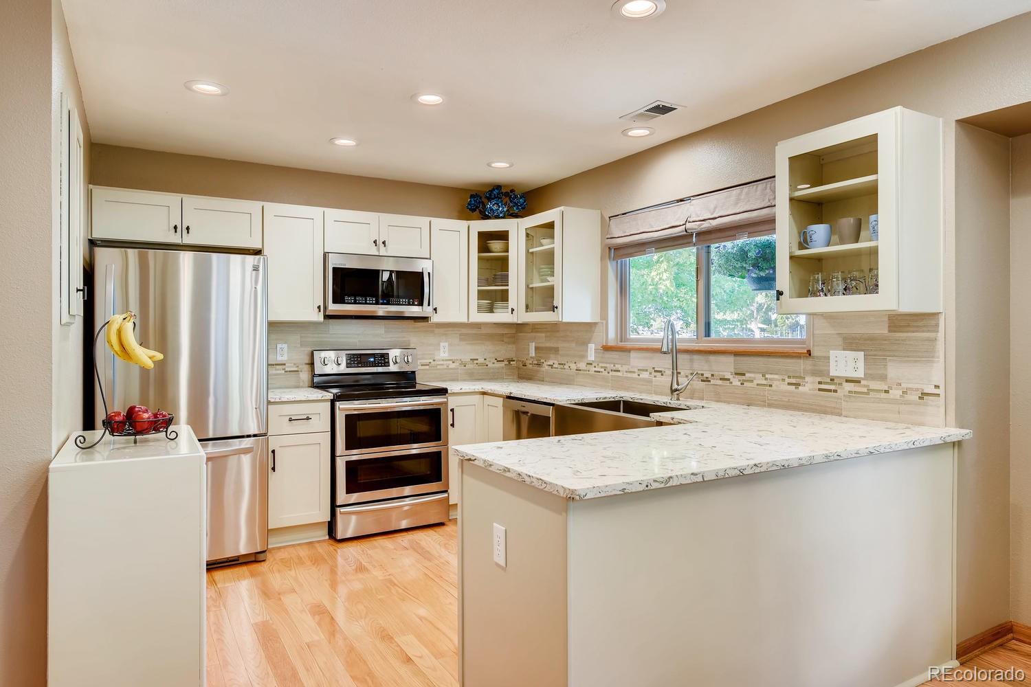 9840 South Castle Ridge Circle Highlands Ranch, CO 80129 - Photo 5 of 28 a kitchen with stainless steel appliances granite countertop a stove top oven a refrigerator a sink and a microwave