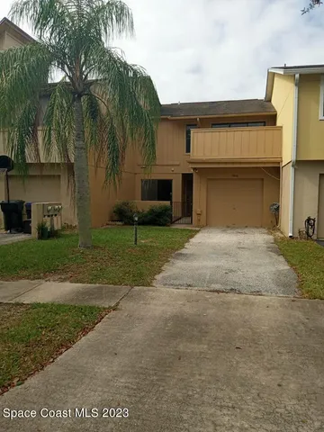 a front view of a house with a yard and palm trees