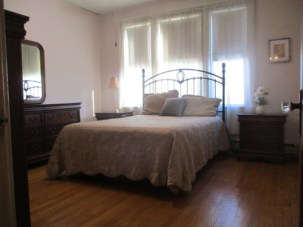 84 Tudor Street, Unit 4 Chelsea, MA 02150 - Photo 12 of 16 a bedroom with a bed lamp and wooden floor