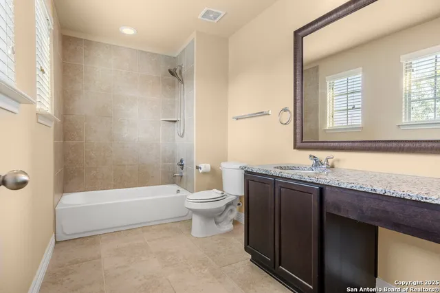 a bathroom with a granite countertop sink a toilet and bathtub