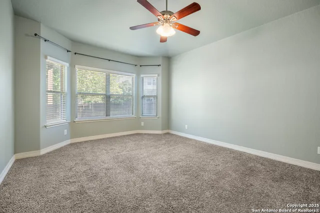 a view of an empty room with window and a kitchen view