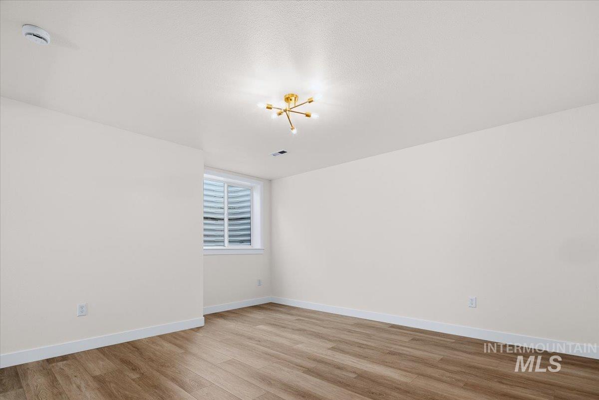 725 North Eagle Road Eagle, ID 83616 - Photo 32 of 45 Spacious room featuring wood-finish flooring, white baseboards, and a modern gold-finish ceiling light fixture