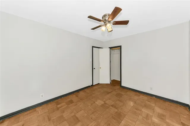 an empty room with window and ceiling fan