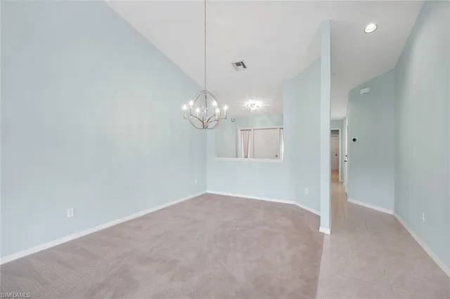 an empty room with a chandelier fan and windows