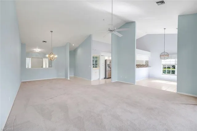 a view of an empty room with kitchen and a window