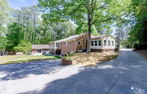 a view of a house with a yard and large trees