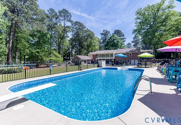 a view of swimming pool with seating space and trees in the background