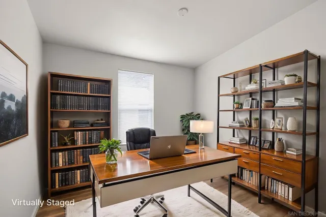 a view of a workspace with bookshelf and a window