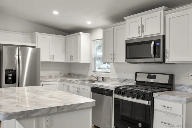 a kitchen with stainless steel appliances granite countertop a stove microwave sink and refrigerator