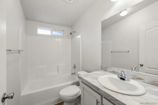 a bathroom with a granite countertop sink a toilet and shower