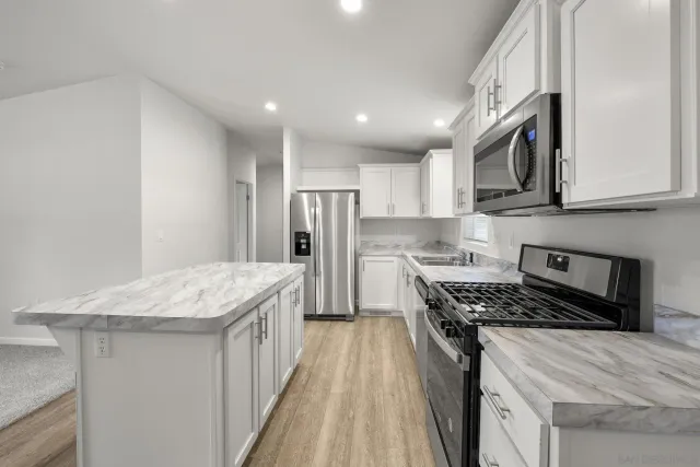 a kitchen with stainless steel appliances granite countertop a sink stove and refrigerator