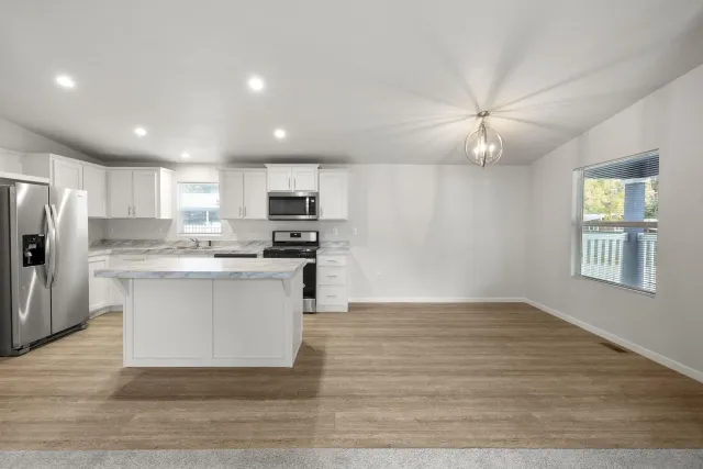 a kitchen with granite countertop a refrigerator stove top oven and cabinets