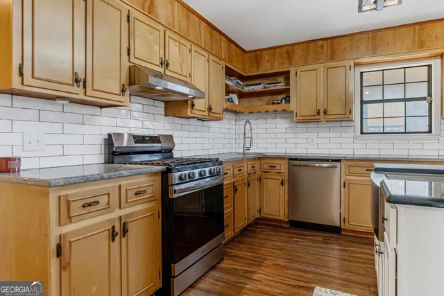 a kitchen with stainless steel appliances granite countertop a refrigerator a stove top oven a sink and dishwasher