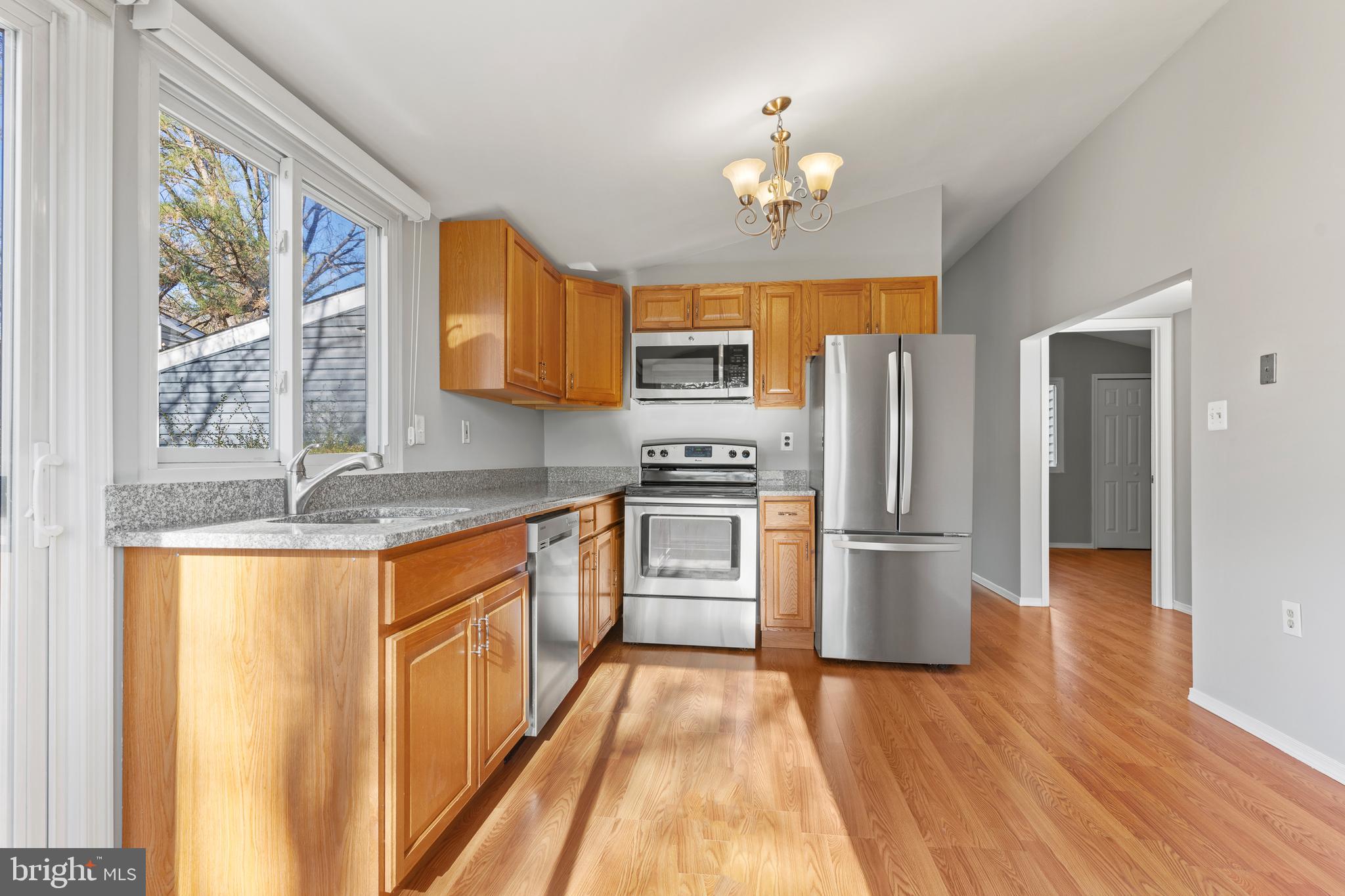 6145 Sinbad Place Columbia, MD 21045 - Photo 11 of 23 a kitchen with stainless steel appliances granite countertop a refrigerator a stove a sink dishwasher and wooden cabinets with wooden floor