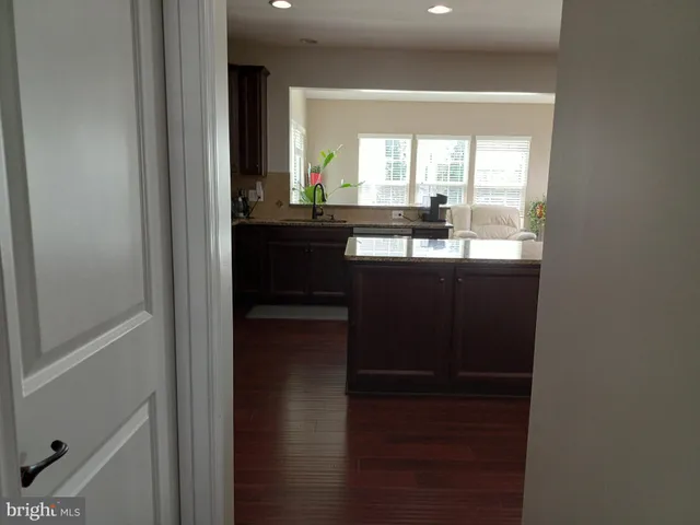 a view of an empty room with wooden floor and a bathroom