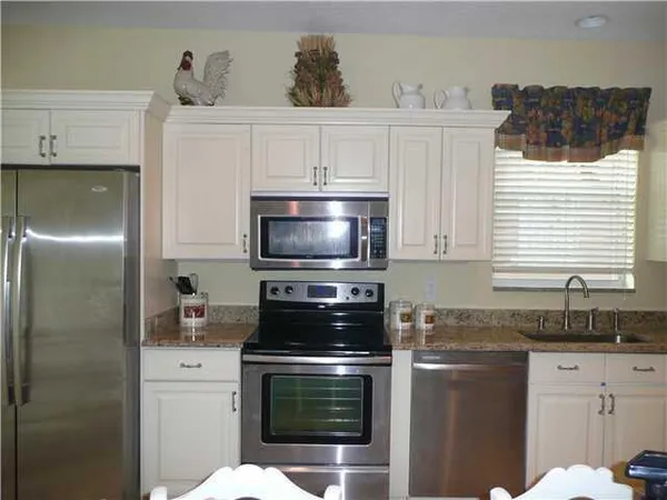 a kitchen with granite countertop white cabinets and stainless steel appliances