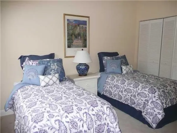 a bedroom with two large bed and a lamp on dresser