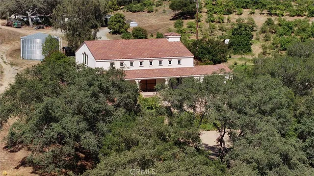 an aerial view of a house with yard and trees all around