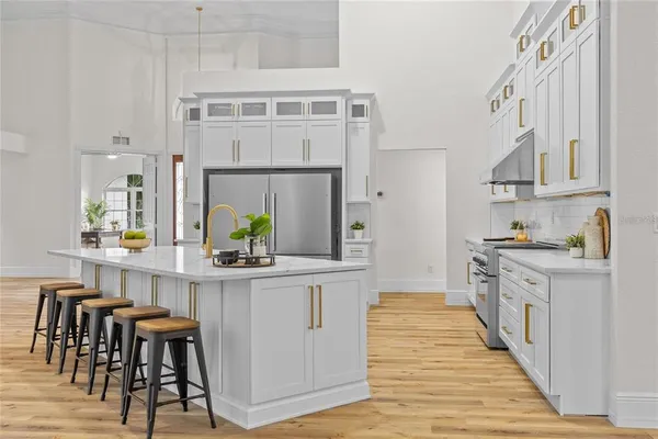 a room with kitchen island stainless steel appliances a stove a sink a refrigerator and cabinets