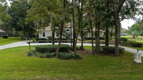 an aerial view of a residential houses with outdoor space and trees