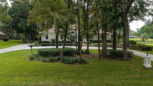 an aerial view of a residential houses with outdoor space and trees