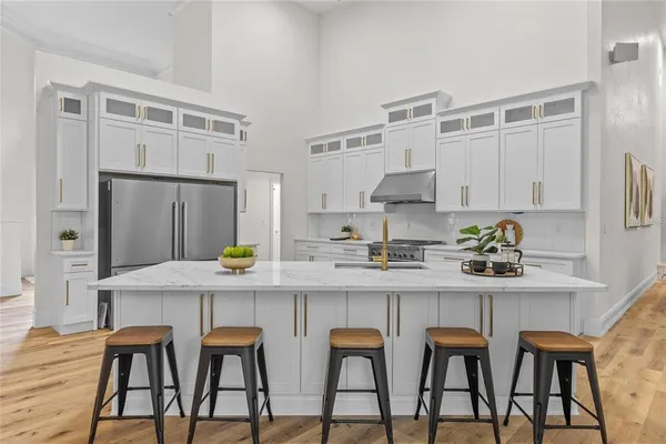 a kitchen with stainless steel appliances a white table chairs and a refrigerator