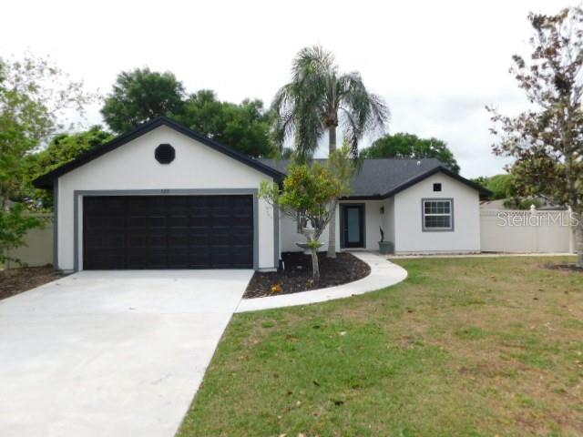 a front view of house with yard and trees in the background